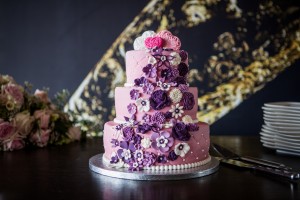 Bruidstaarten - roze bruidstaart met waterval aan paarse en witte bloemen Bruidstaarten - roze bruidstaart met waterval aan paarse en witte bloemen